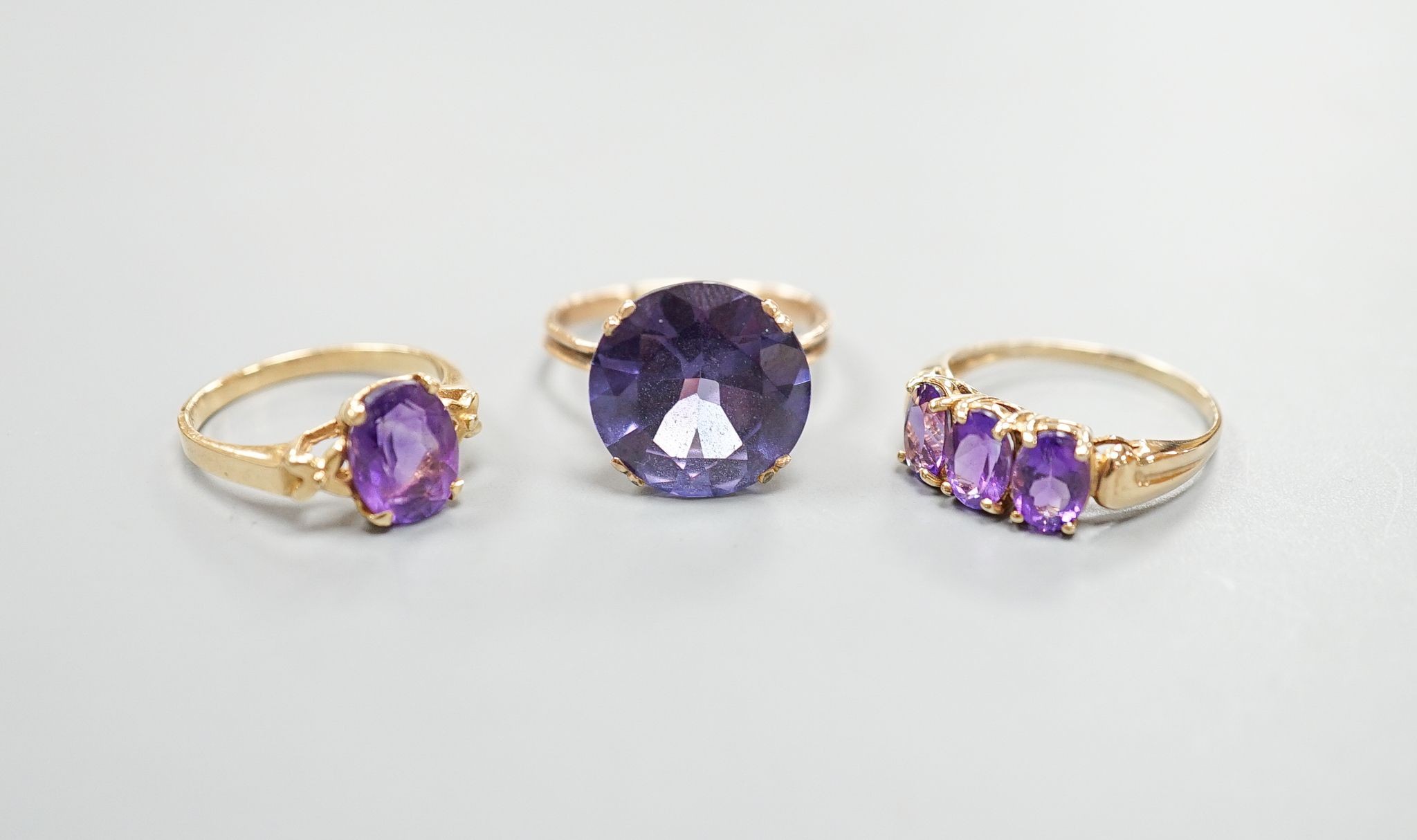 Two modern 14k yellow metal and gem set rings, including amethyst, size N, gross weight 7.4 grams and a similar 10k and three stone amethyst ring, size Q/R, gross 2.3 grams.